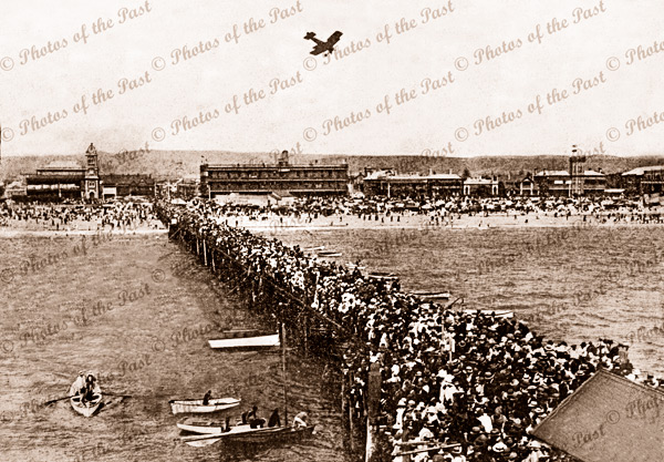 Harry Butler flying over Glenelg 28 December 1919. Horizontal format. South Australia. Jetty. Crowds.