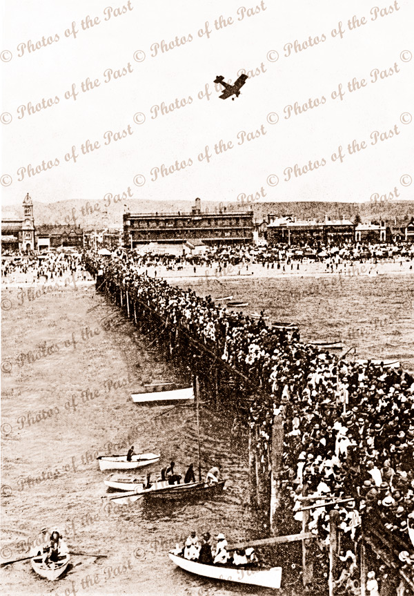 Harry Butler flying over Glenelg 28 December 1919. Veritical format. South Australia. Jetty. Crowds.