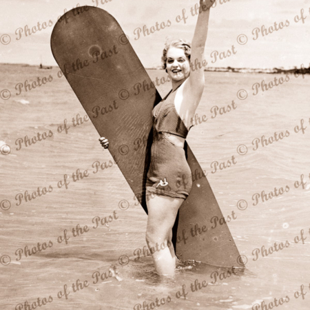 Girl with old surf board in water. c1940s