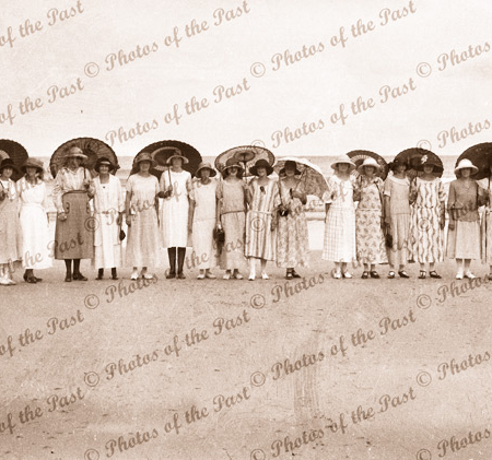 16 beach belles sharing eight parasols on Spout Beach Eastern View, Victorian. c1920s.
