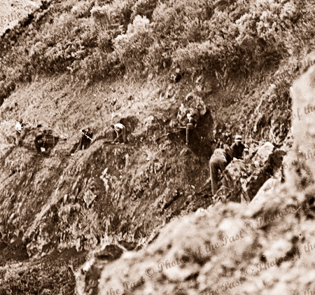 onstruction of Great Ocean Road. Workers carve the start of track across a steep slope with pick & shovel. A team before has cleared the vegetation. Distant and near views available. c192