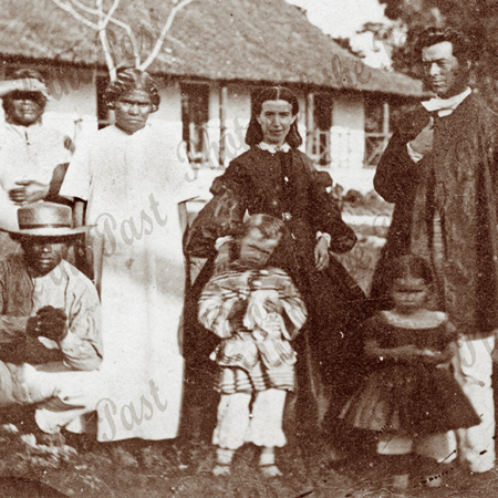 Reverend & Mrs McFarlane with thir two children & locals at Lifou, one of the Loyalty Islands. (Provence of New Caledonia). Outside their house. c1864